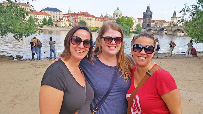 3 girls by the prague riverside with charles bridge in background