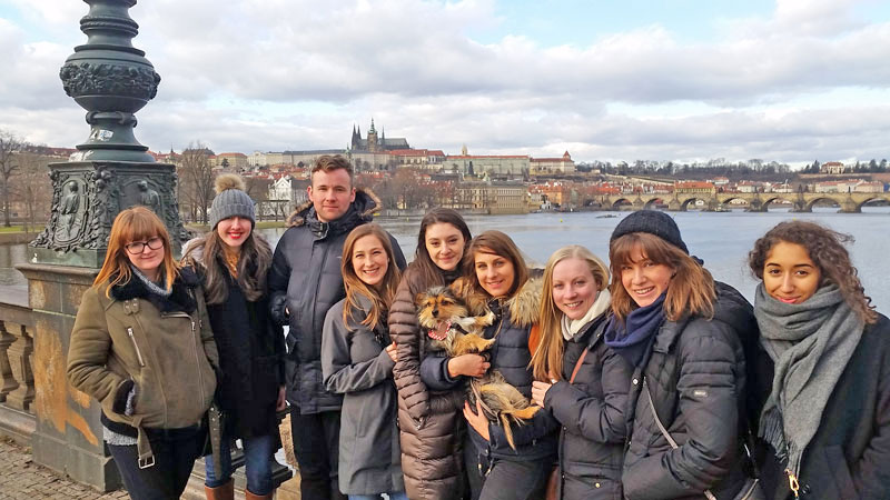 group standing by the riverside with prague castle in the background